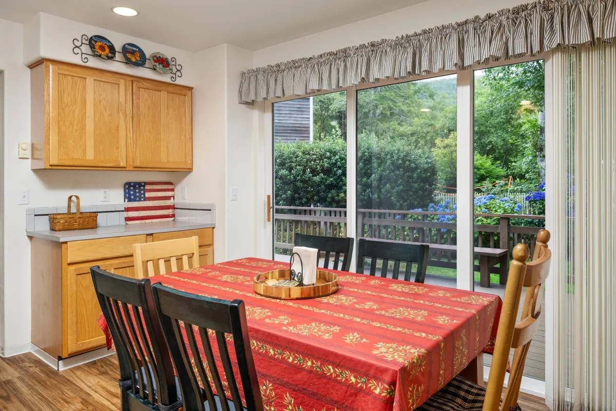 A cozy dining area is set next to sliding glass doors, connecting the kitchen with the outdoors. The table is ready for shared meals and socializing after a day of village strolls or golf, while the kitchen in the background suggests the ease of preparing local finds.